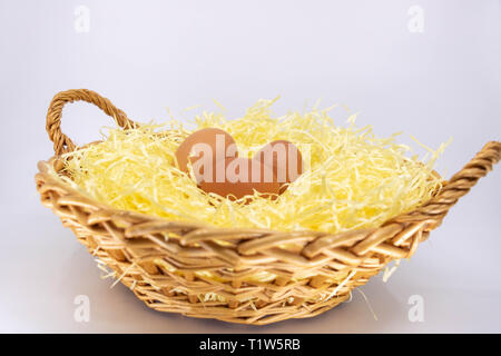 Le uova organiche dalla fattoria in un cesto di vimini riempito con paglia Foto Stock