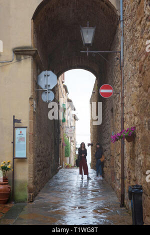 Pienza/Italia - 05/05/18: due donne nascosto dalla pioggia sotto il vecchio arco in Pienza, una delle più belle città vecchia in Toscana, Italia Foto Stock