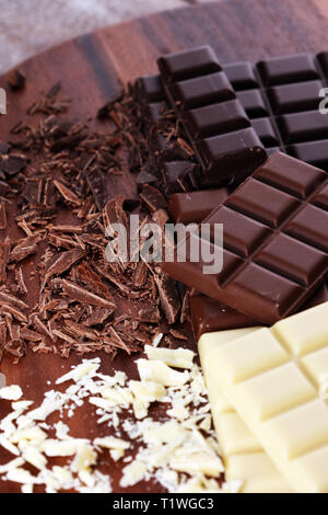 Cioccolato in vari colori. latte, cioccolato fondente e bianco bar e pezzetti di cioccolato Foto Stock
