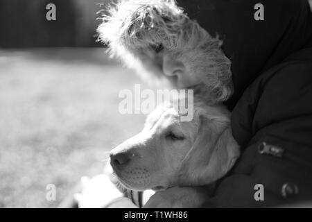 Una donna che abbraccia il suo labrador in inverno. Foto Stock