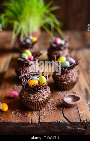 Nido di pasqua tortini di cioccolato con panna montata e decorate con uova colorate Foto Stock