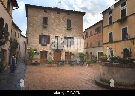 Pienza, Italia - 05 Maggio 2018: bella strada stretta con la luce del sole e fiori nel piccolo magico e antico borgo di Pienza, Val d'Orcia Toscana. Foto Stock