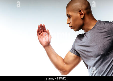 Uomo concentrato per dimostrare la sua potenza mentre si fa sport Foto Stock