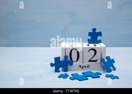 Blue i pezzi del puzzle in piedi con il calendario sul blu sullo sfondo di legno Foto Stock