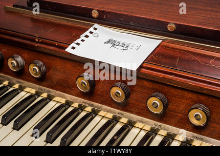 Le note musicali scritte su un pezzo di carta seduto su un organo vintage Foto Stock