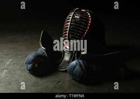 Guanti di Kendo e casco tradizionale sulla superficie scura Foto Stock