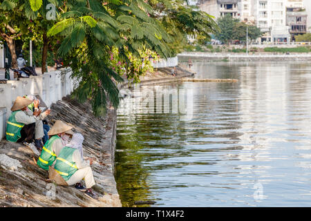 Lavoratori vietnamiti in appoggio vicino a Quan Tay Ho oppure Westlake del distretto di Hanoi. In riva al lago dei Tay con residentian edifici e ristoranti. Il Vietnam. Foto Stock