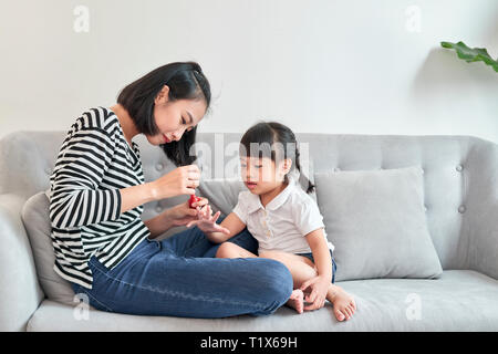 Giovane e bella madre è la pittura di smalto per le unghie per la sua incantevole piccola figlia Foto Stock