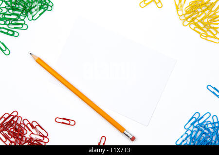 Matita, fermagli per carta si trovano in diversi angoli del foglio su uno sfondo bianco. Immagine Hero e spazio di copia Foto Stock