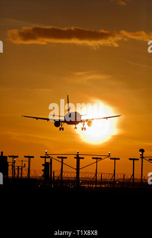 Aereo di linea in atterraggio a Heathrow airport al tramonto Foto Stock