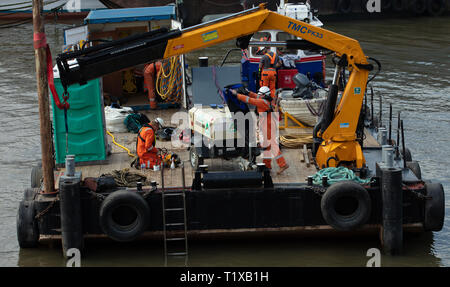 Un equipaggio di lavoratori di manutenzione su una piattaforma galleggiante scompare dopo che un subacqueo sbloccati un sottomarino di scarico sul fiume Tamigi, Londra, Inghilterra, Regno Unito. Foto Stock