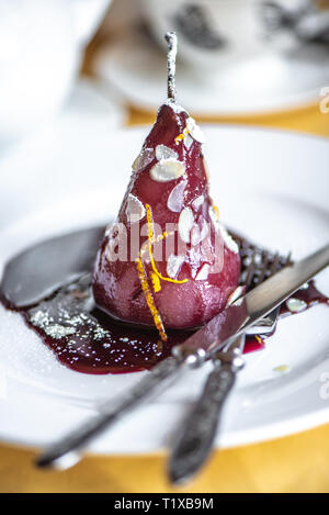 Pera in vino. Tradizionale dessert pera stufati nel vino rosso su sfondo giallo. Foto Stock