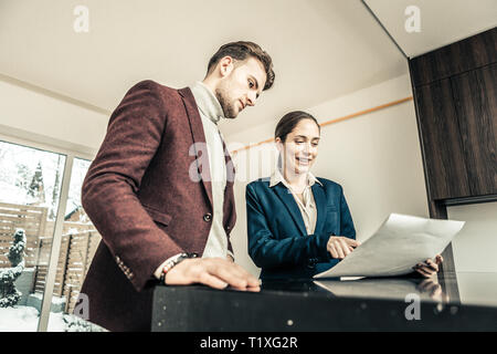 Barbuto dai capelli scuri che indossa uomo dark red jacket parlando di agente immobiliare Foto Stock
