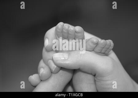 Madre mentre tiene il suo bimbo di piedi Foto Stock