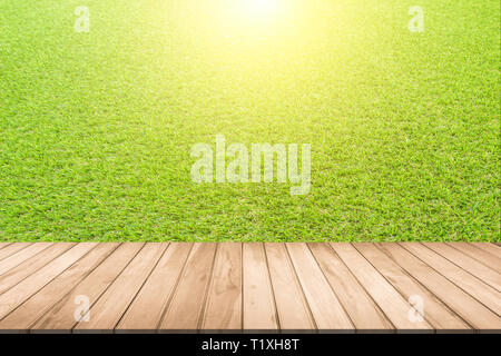 Vista laterale vuoto tavola di legno verde in primavera o in estate il giardino picnic sulla natura. Terrazza di legno ed erba verde campo parco pubblico impiego come backgrou naturale Foto Stock