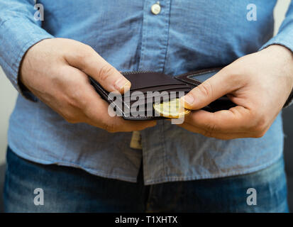 Uomo con la versione fisica di golden bitcoin. Foto Stock