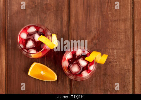 Due cocktail vivaci con Campari e orange curl contorni, con una fettina d'arancia, girato dalla parte superiore al buio su un rustico sfondo di legno Foto Stock