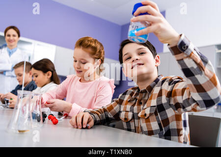 Curioso alunni seduti alla scrivania e studiare la chimica in aula Foto Stock