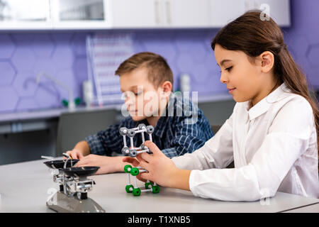 Gli studenti azienda strutture molecolari seduti in classe durante la lezione di Chimica Foto Stock