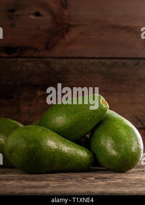 Pila di con la buccia verde brillante avocadi su legno tavolo rustico Foto Stock