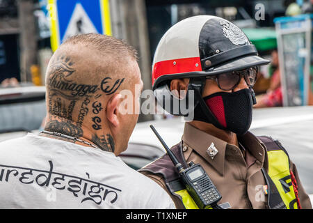 Phuket, Thailandia 17 Gennaio 2019: l'Uomo con testa tatuata a parlare con il poliziotto a Patong Beach. La polizia spesso fini turisti per reati di traffico. Foto Stock