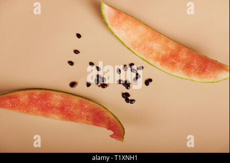 Due mangiato fette di anguria con semi su sfondo marrone con vista Foto Stock