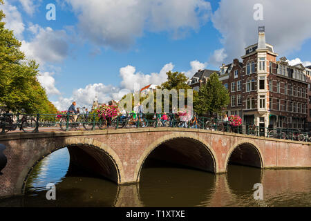 I ciclisti attraversare un ponte sul canale Keizersgracht in Amsterdam, Olanda Settentrionale, Paesi Bassi. Foto Stock