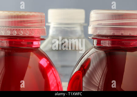 Bottiglie di plastica con colore rosso acqua e acqua trasparente in retro Foto Stock