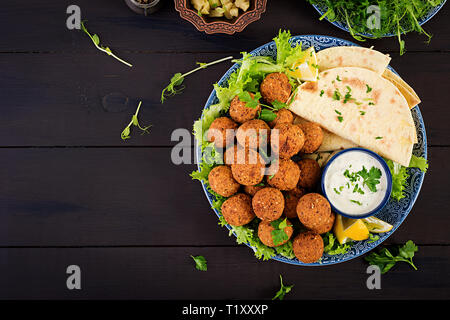 Falafel hummus e pita. Medio orientale o piatti arabi su uno sfondo scuro. Cibo Halal. Vista dall'alto. Spazio di copia Foto Stock