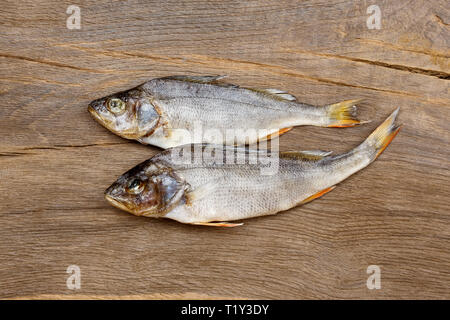 Due pesci essiccati su un tavolo di legno. Foto Stock