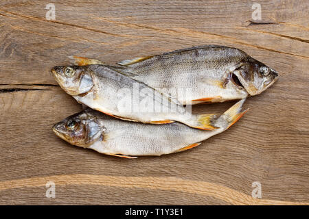 Tre pesci essiccati su un tavolo di legno. Foto Stock
