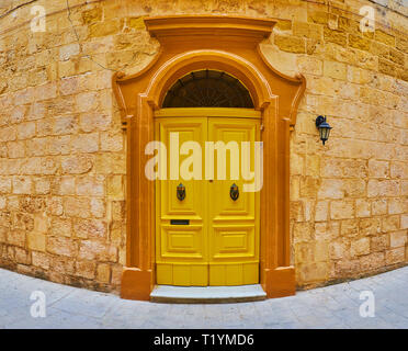 Il living mansion vanta massicci di colore giallo brillante porta in legno con vintage il telaio della porta e il pomello in metallo battenti, Rabat, Malta. Foto Stock