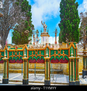 La statua di San Paolo nel piccolo giardino nella vecchia città di Rabat, circondato da un enorme muro di pietra e decorazioni del festival, Malta. Foto Stock