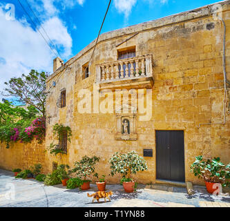 La villa medievale nella vecchia città di Rabat, decorata con balcone in pietra e la scultura di Sant Agata in nicchia, Malta. Foto Stock