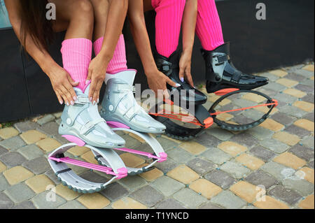 Due donne mettere su kangoo jumping stivali prima di allenamento. Closeup shot con le mani Foto Stock