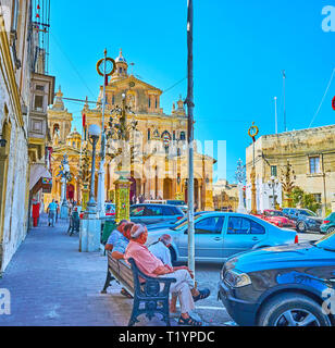 Aberdeen, Regno Unito - 16 giugno 2018: la società di senior uomo Maltese si siede sul banco di fronte alla chiesa di St Nicholas, il 16 giugno a Siggiewi Foto Stock