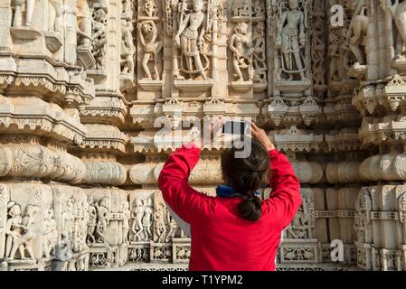 INDIA RAJASTHAN, RANAKPUR, 2013-12-23: Donna di scattare le foto con uno smart phone di sculture a Ranakpur temple Foto Stock