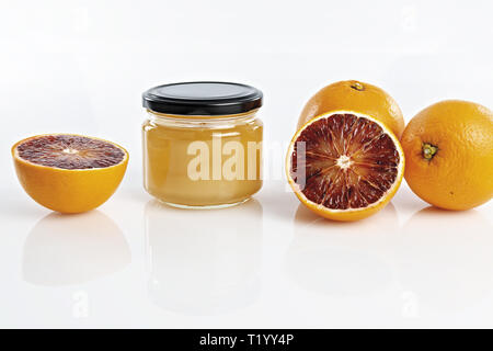 Miele all'arancio in vaso con arance tagliate fronte Foto Stock
