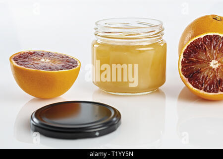 Miele all'arancio in vaso con arance tagliate. primo piano altra vista Foto Stock