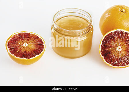 Miele all'arancio in vaso con arance tagliate da sopra Foto Stock
