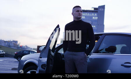 Imprenditore bello vicino alla sua auto in città Foto Stock