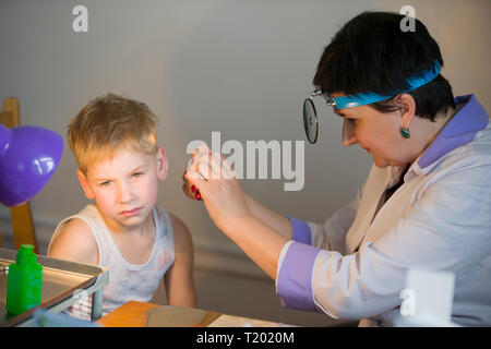 La Bielorussia città Dobrush Luglio 12, 2018. Bambini ospedale centrale. Bambino otolaryngologist esamina il paziente. Il medico considera un mal di orecchio per un bambino. Foto Stock