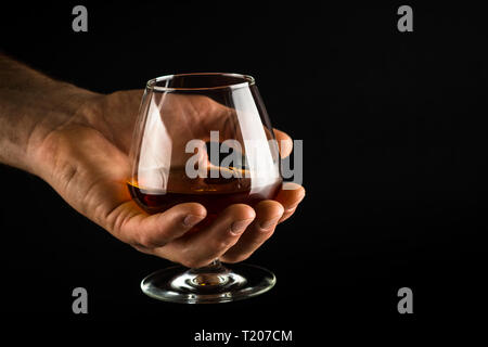 Man tenere il Cognac o brandy di vetro in mano. Foto Stock