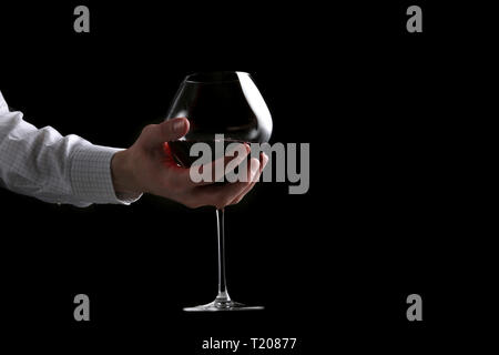 Mans tenere in mano il vetro di vino isolato su sfondo nero. Foto Stock