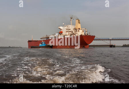 Operazioni portuali per la gestione e il trasporto di minerali di ferro.Tirare la manovra e girando il trasbordo nave prima di docking e di carico di minerale fino al molo Foto Stock