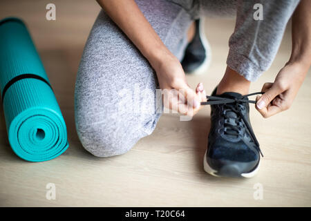 Close up della donna la legatura dei lacci delle scarpe da ginnastica prima di esercitare a casa Foto Stock