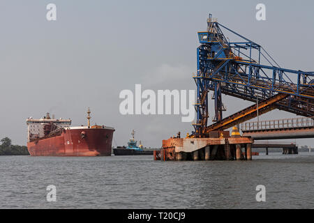 Operazioni portuali per la gestione e il trasporto di minerali di ferro.Tirare la manovra e girando il trasbordo nave prima di docking e di carico di minerale fino al molo Foto Stock