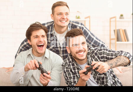 I videogamer accaniti. Uomini eccitati alla riproduzione di video gioco, incontro e divertimento a casa Foto Stock