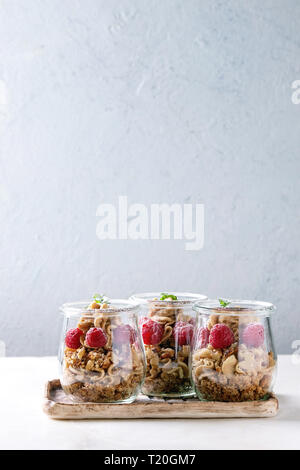 Layered dessert in vasi. Biscotti, caffè crema, dadi, lamponi e menta fresca. Servita sul vassoio in ceramica su marmo bianco tavola. Foto Stock