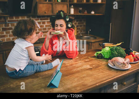 La madre e il bambino insieme impegnati in faccende di casa la stiratura di panni . Casalinga e kid facendo i compiti. Donna con bambino nel soggiorno. Homemake Foto Stock